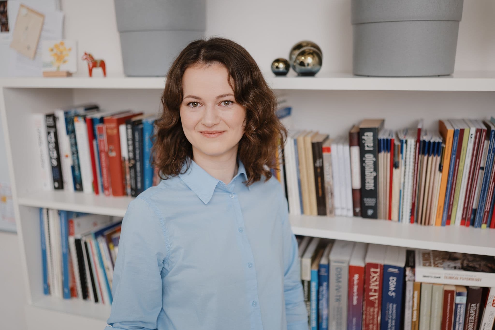 Dr. Austėja Dumarkaitė prie knygų lentynos